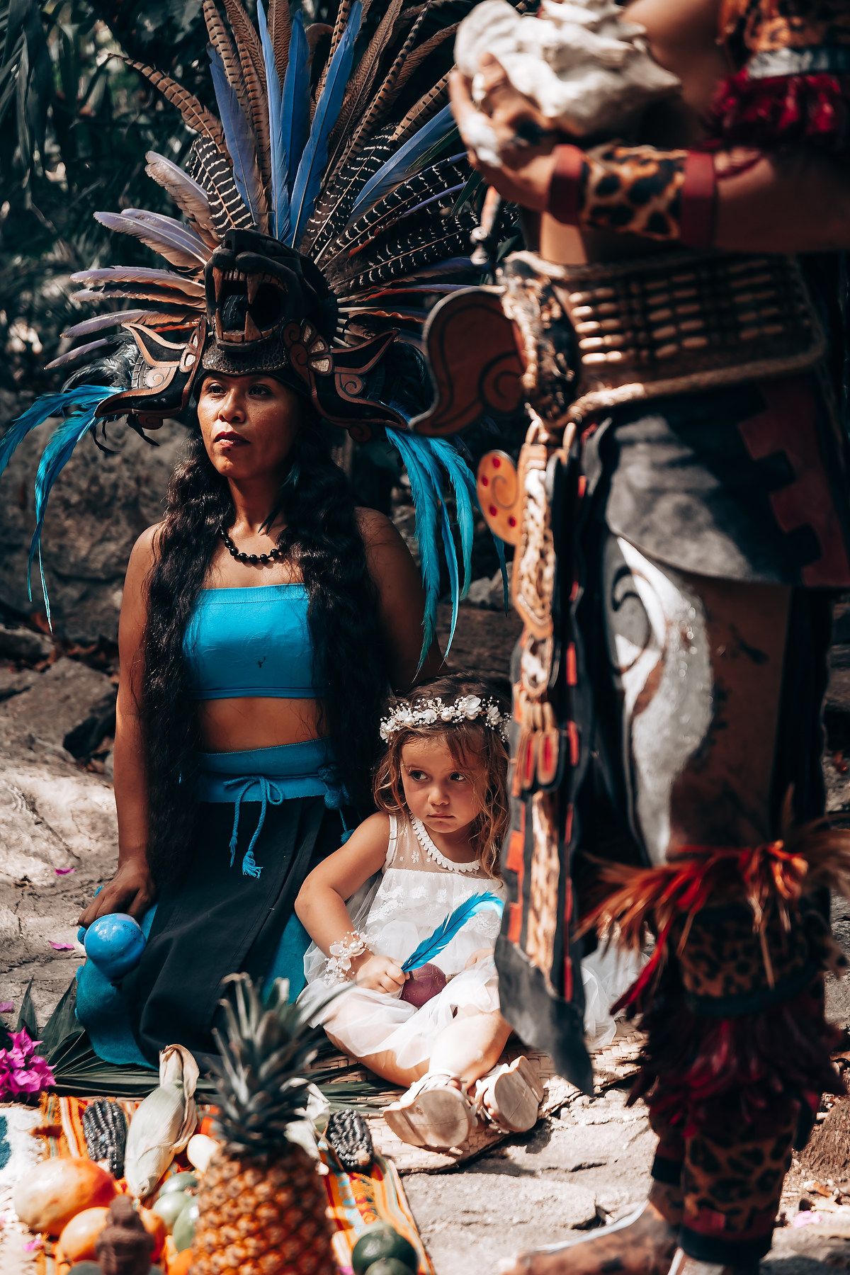 Traditional Mexican ceremony with dancers in vibrant blue outfits and feathered headdresses performing outdoors.