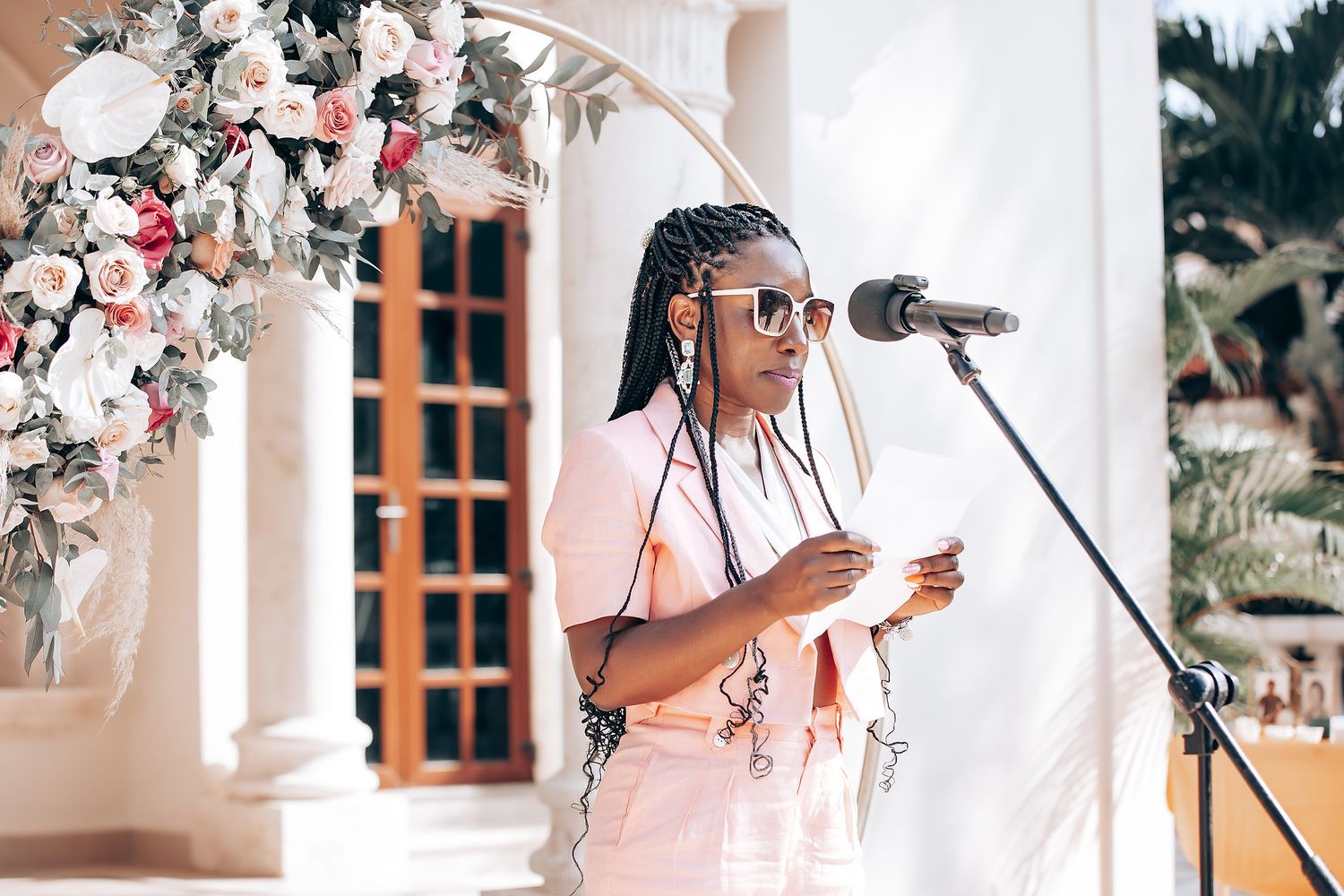 Wedding ceremony decor featuring pink floral arrangements and white columns.