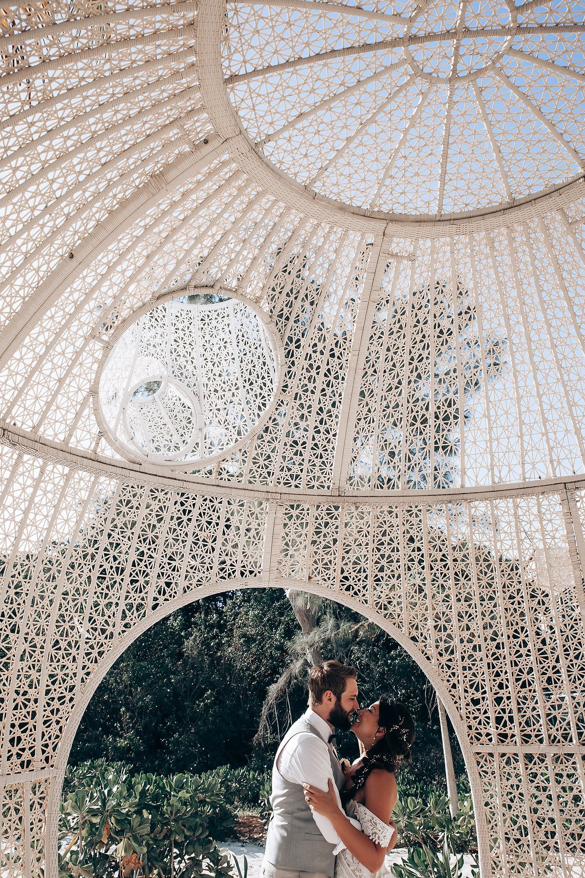 Ornate white gazebo with intricate lattice dome creates a romantic outdoor wedding ceremony setting.