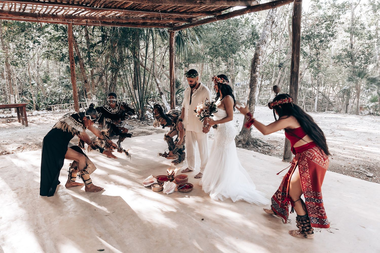 Guests gather under a rustic wooden pergola during a celebration.