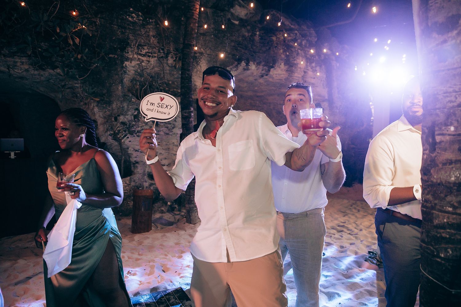 Wedding guests dancing and mingling at an evening reception with ambient lighting.