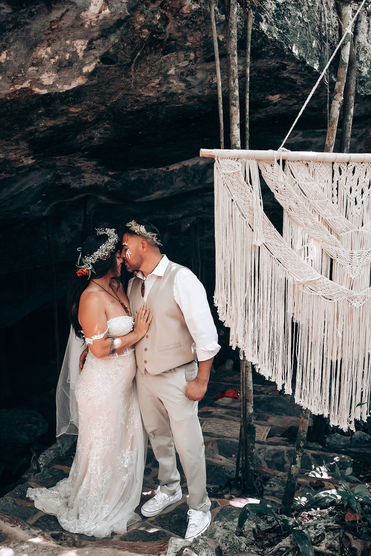 Wedding ceremony moments photographed in a cave with hanging macrame decorations creating a bohemian atmosphere.