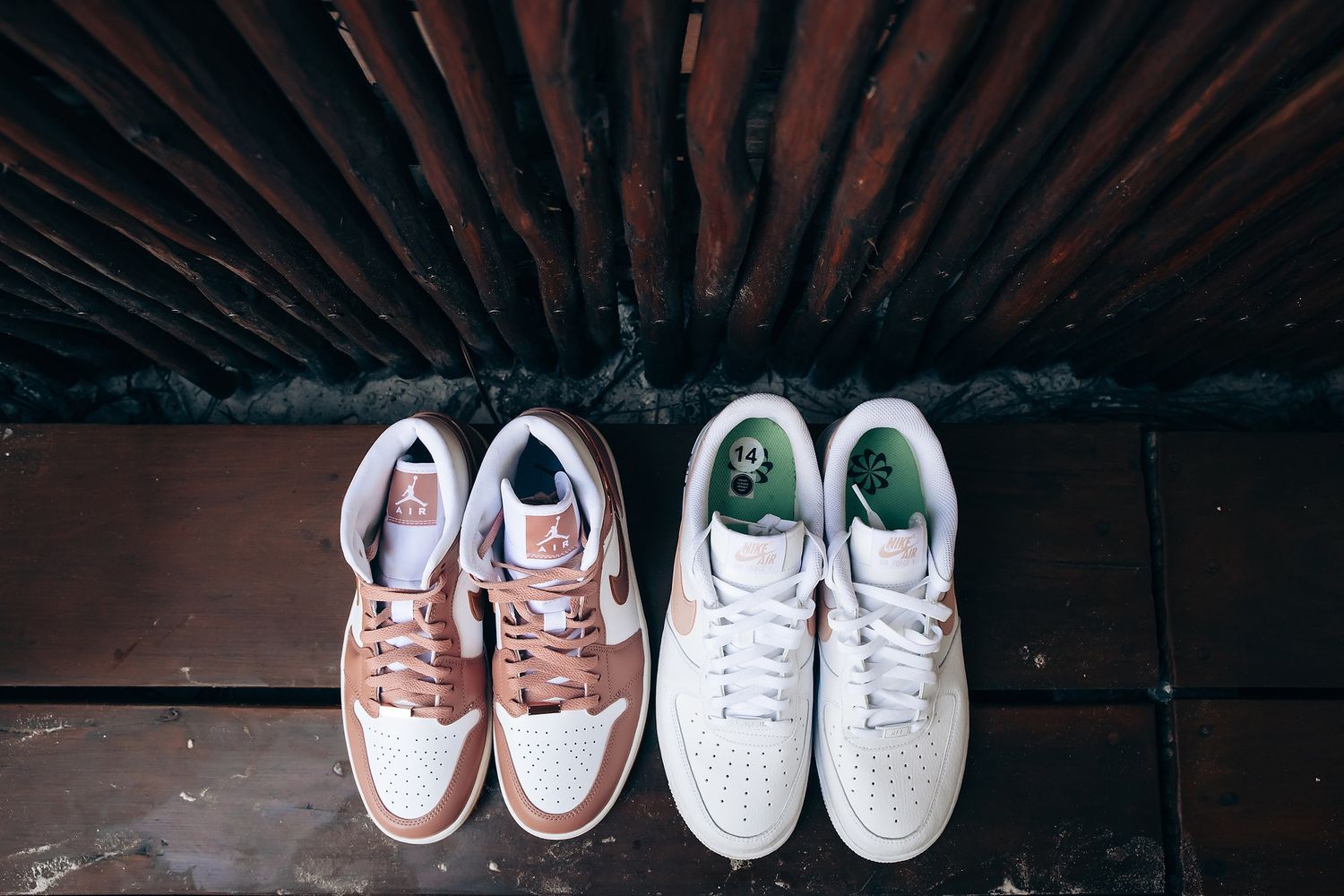 The image shows two pairs of sneakers, one white and one pink, placed on a wooden surface.