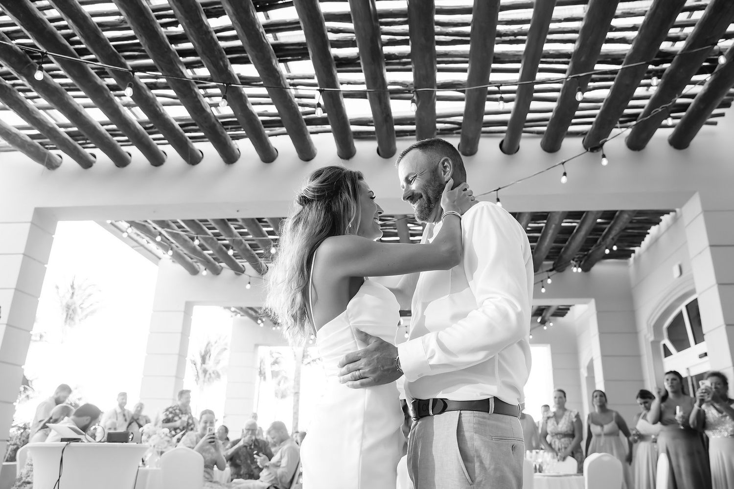 A couple in wedding attire holding hands and walking together in a tropical setting.