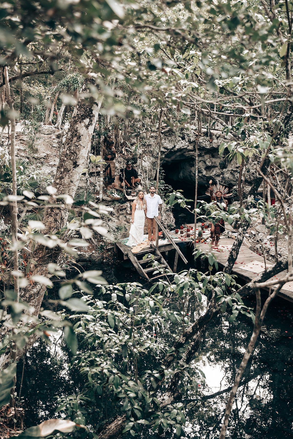 Aerial view of wedding ceremony taking place on wooden platform over jungle cenote.