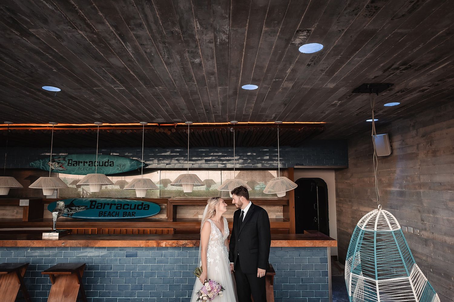 Wedding venue interior with rustic wooden ceiling and industrial lighting.