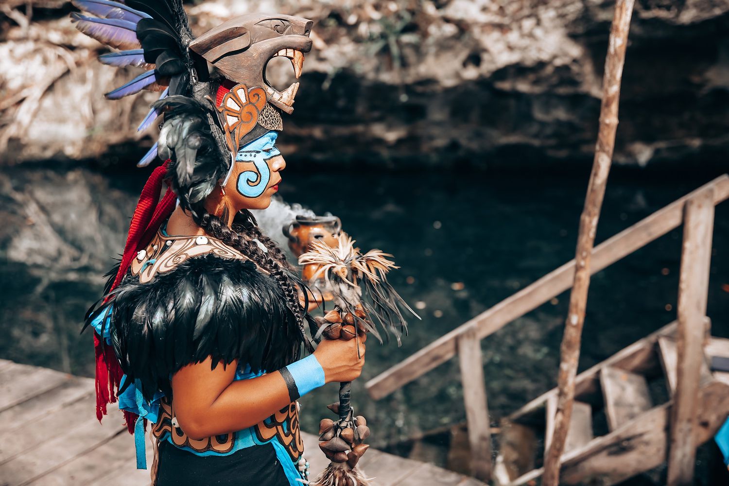 A person wearing an elaborate Native American headdress and traditional regalia performs at a cultural ceremony.