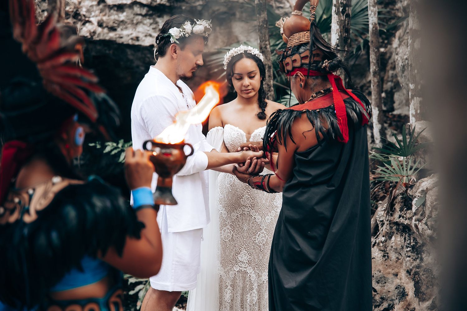 A couple shares an intimate moment during an outdoor wedding ceremony against a rustic stone wall background.