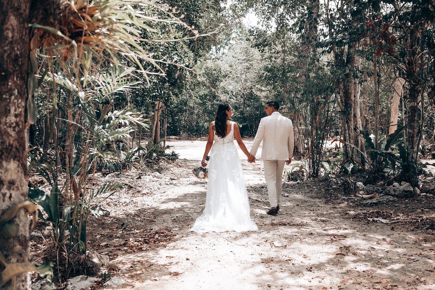 Newlyweds walking through a serene forest path after their ceremony.