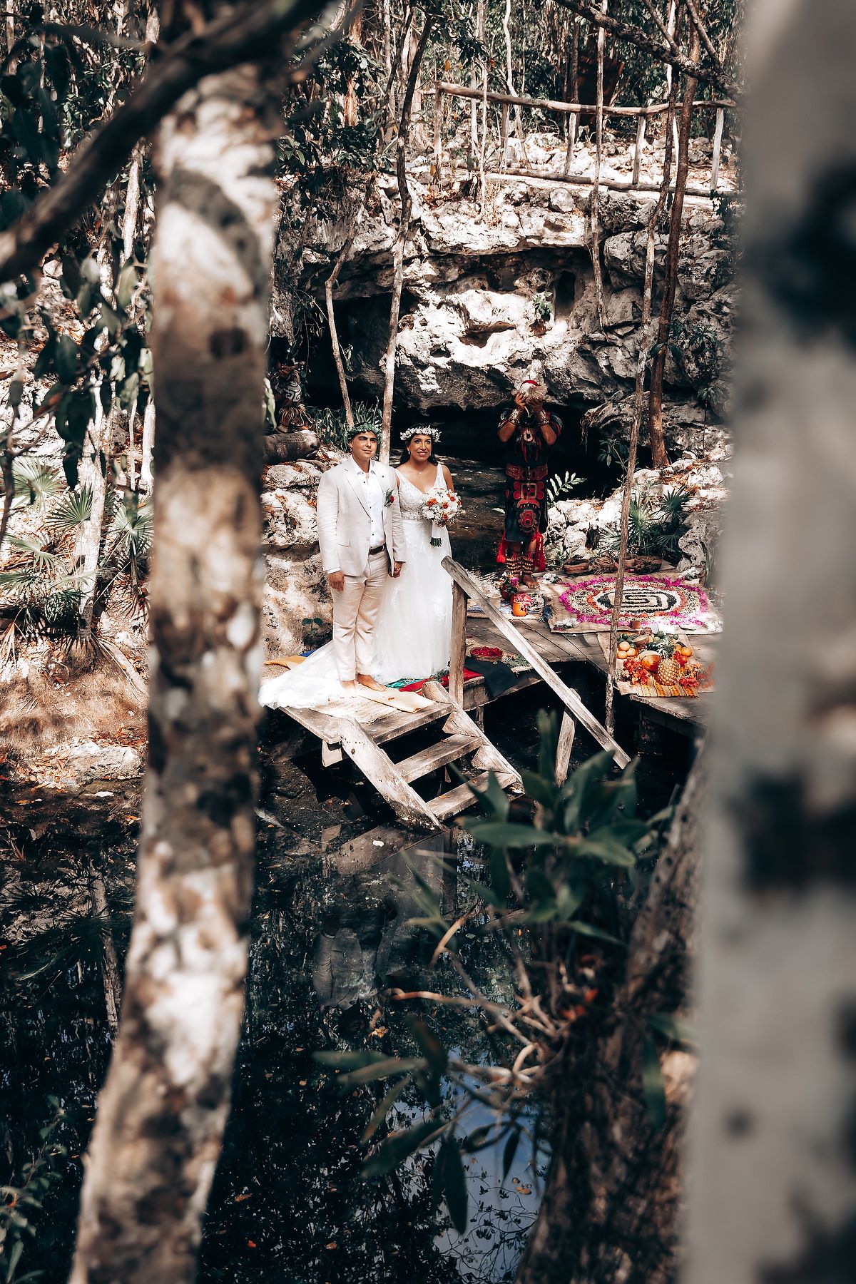 Outdoor wedding ceremony setup in a forest with white decor and rustic elements.