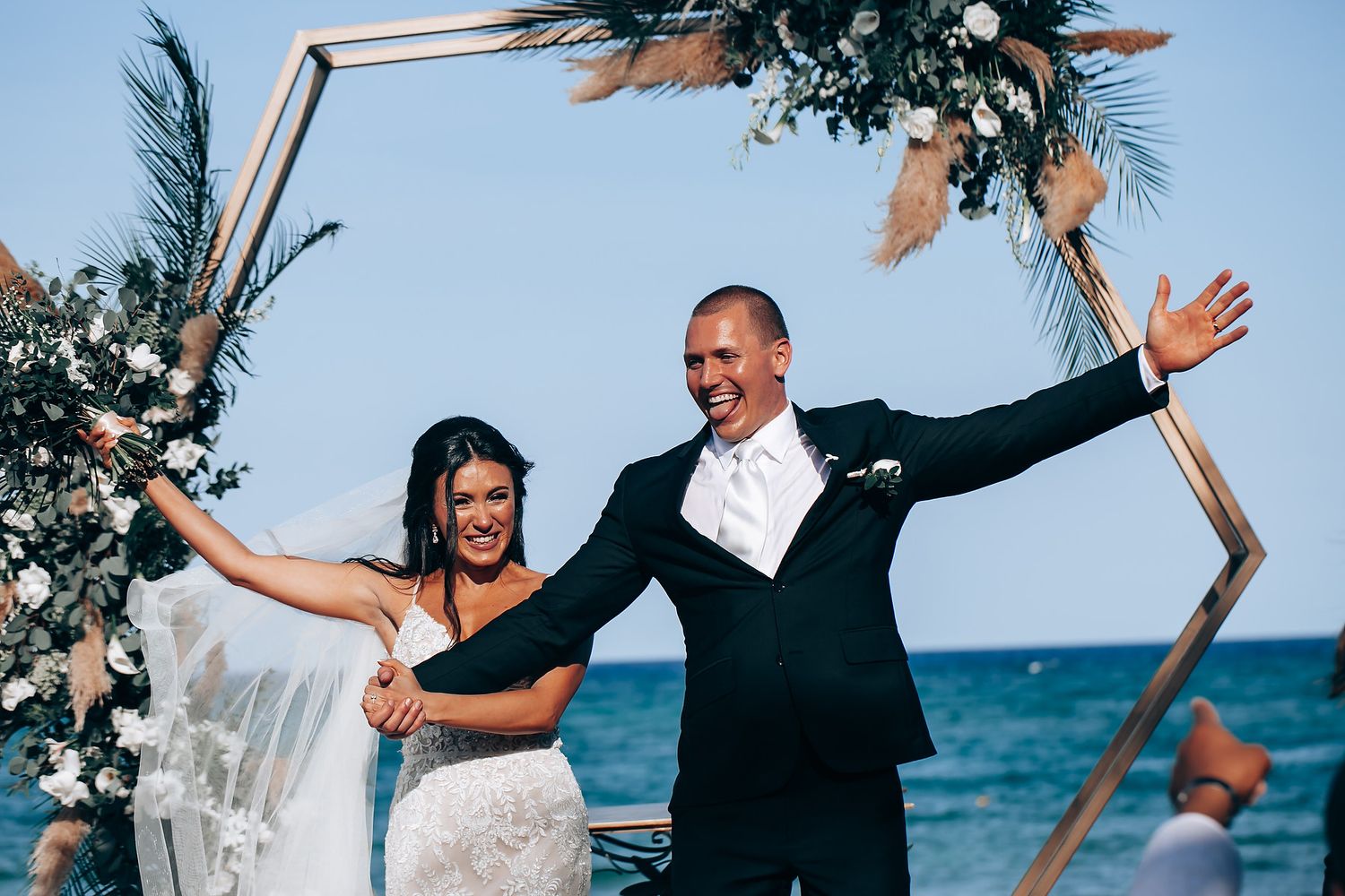 Joyful celebration during beach wedding ceremony with tropical decorations.