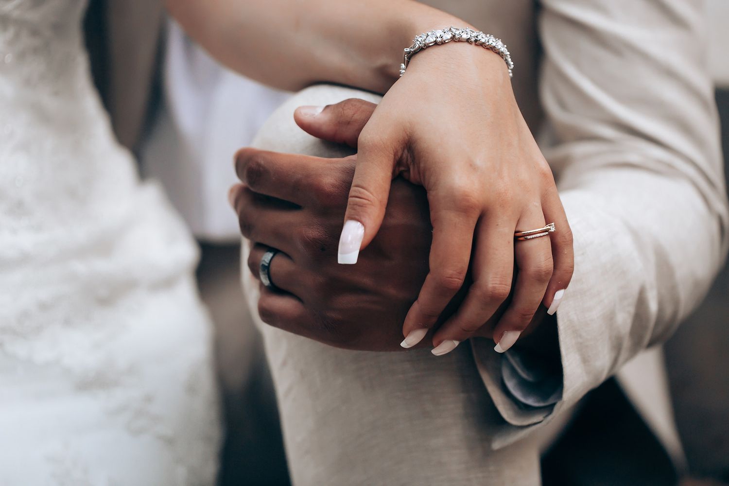 Close-up of hands wearing wedding rings during ceremony.