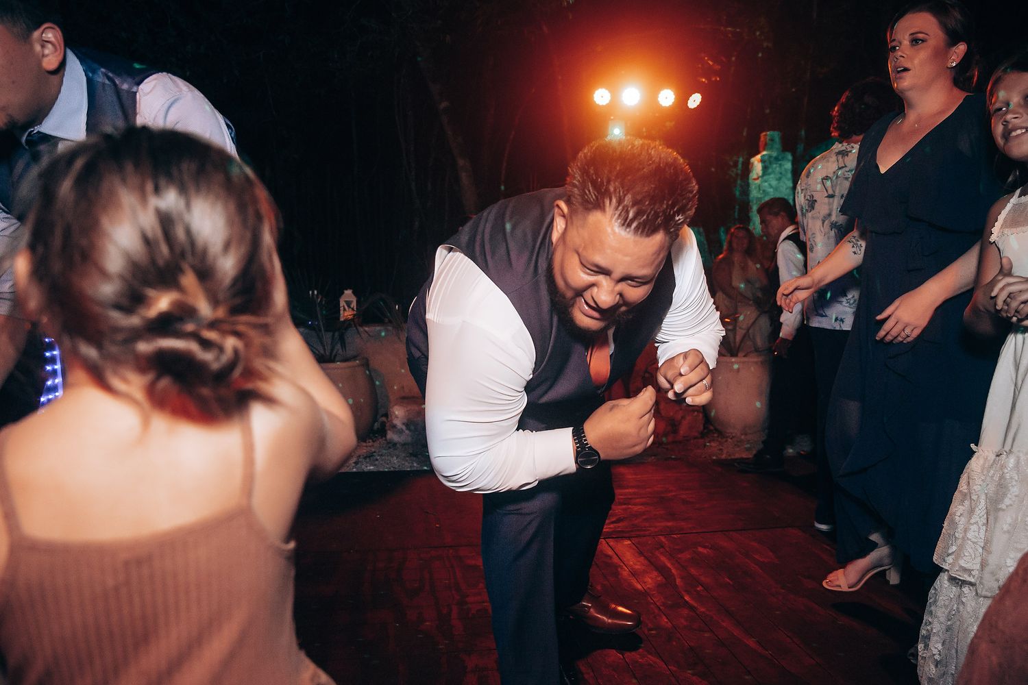 Wedding guest dancing energetically on outdoor dance floor at night.