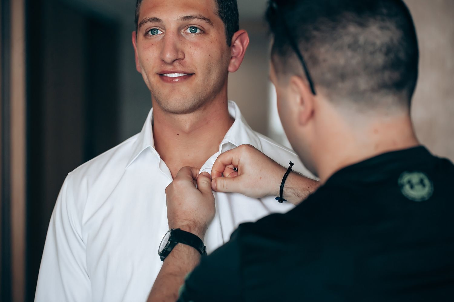 Wedding preparations showing groomsmen getting ready in a casual indoor setting.