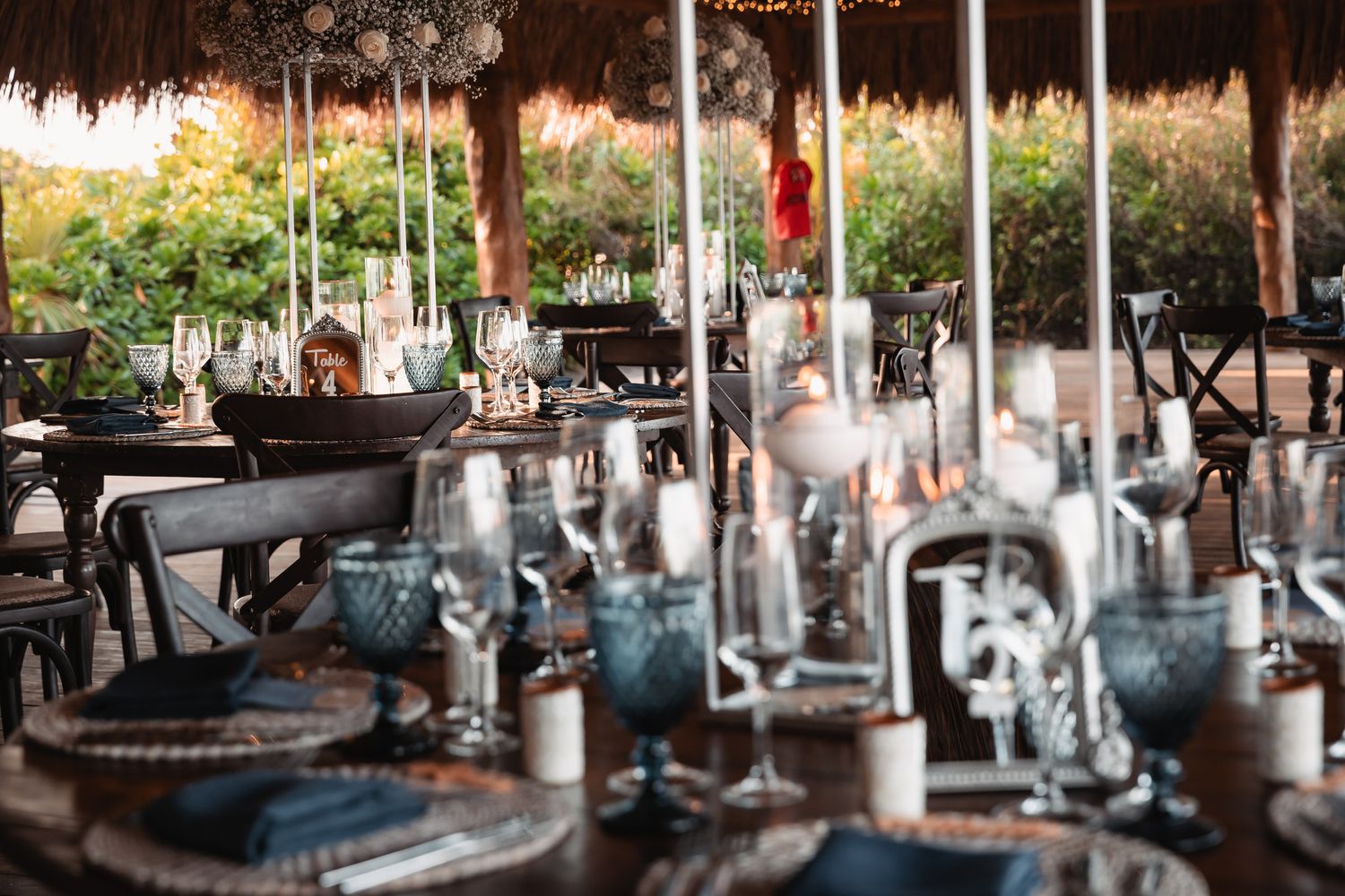 Romantic outdoor wedding reception table setting with blue glassware, candles, and elegant centerpieces.