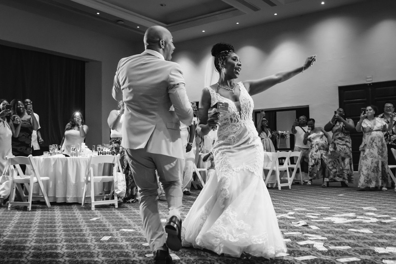 Black and white photo of a bride and groom sharing their first dance at a wedding reception in a ballroom.
