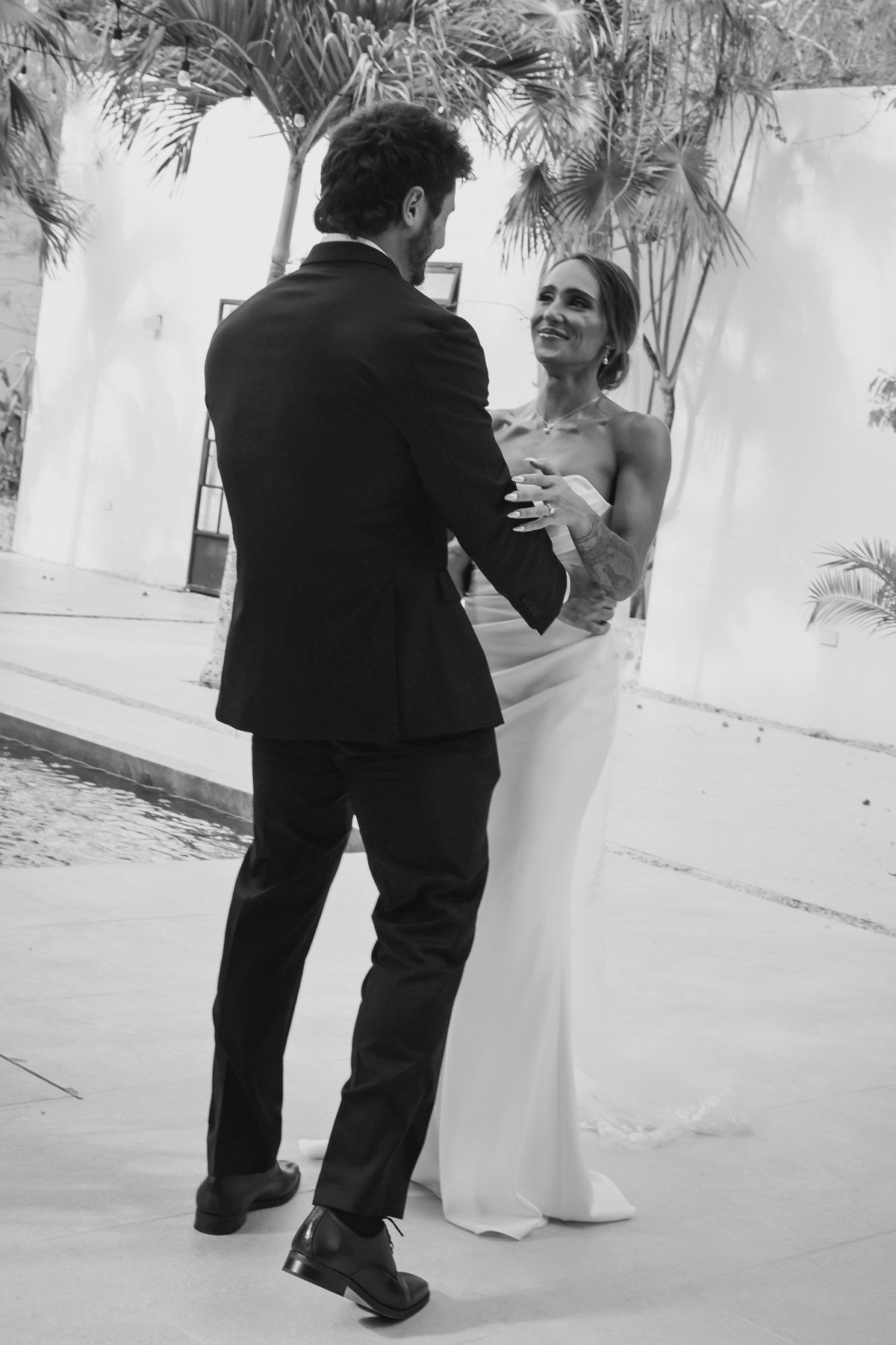 Bride and groom share their first dance at an elegant outdoor wedding in black and white photo.