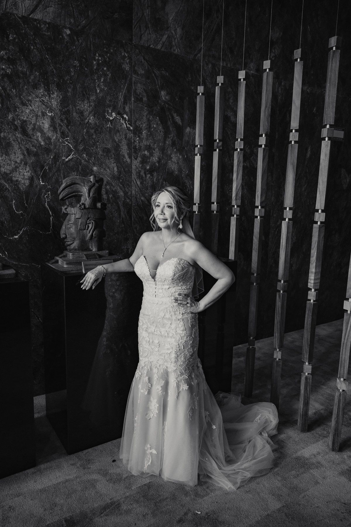 Bride in strapless lace mermaid wedding gown posing elegantly in black and white portrait.