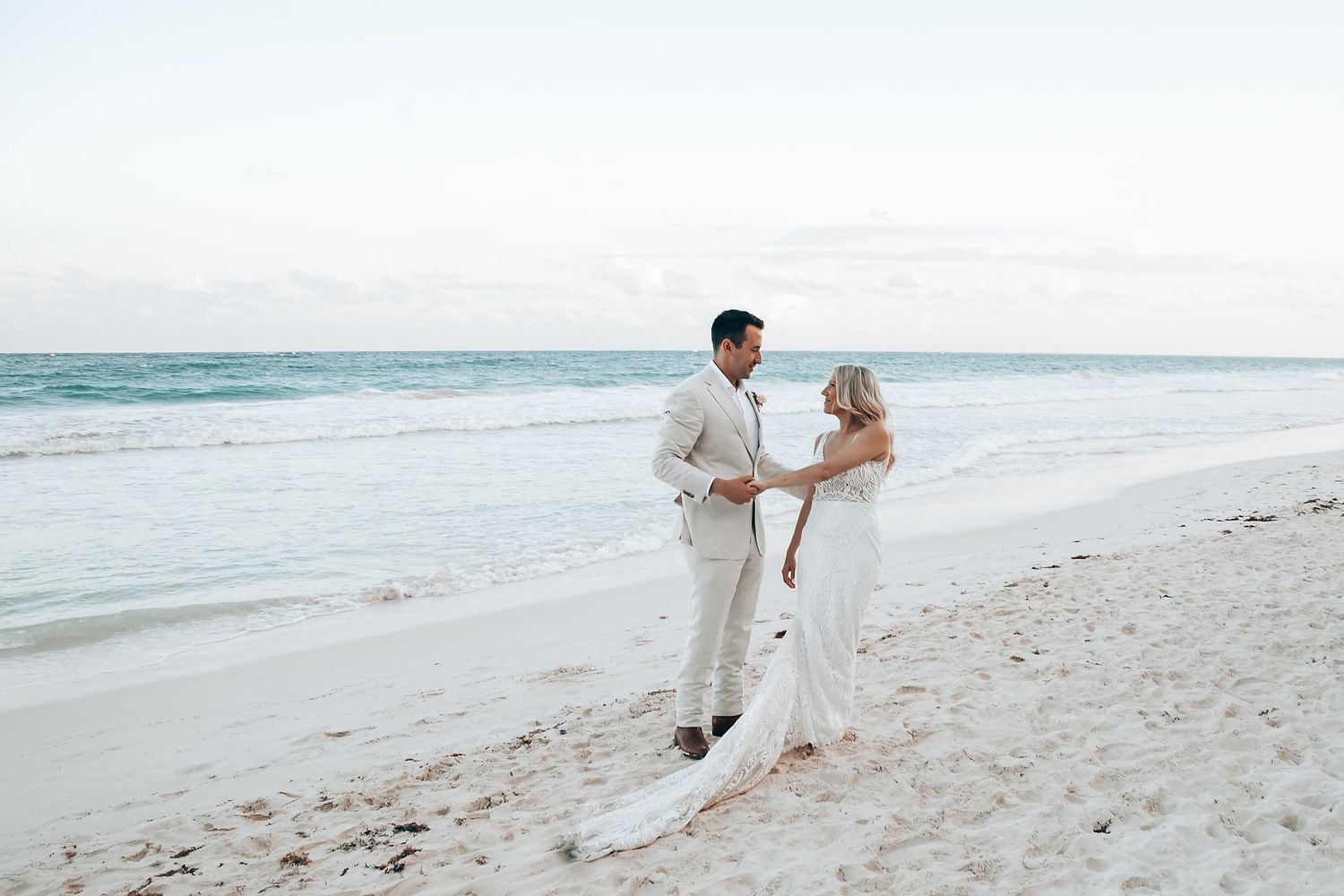 Couple walking along a pristine white sand beach at their tropical destination wedding.