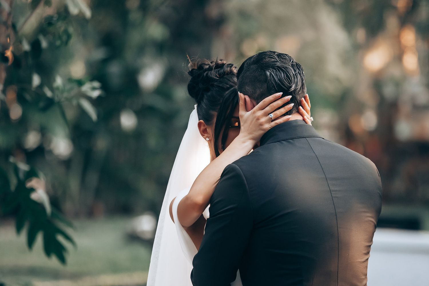 Romantic outdoor garden wedding ceremony with couple embracing under natural greenery.