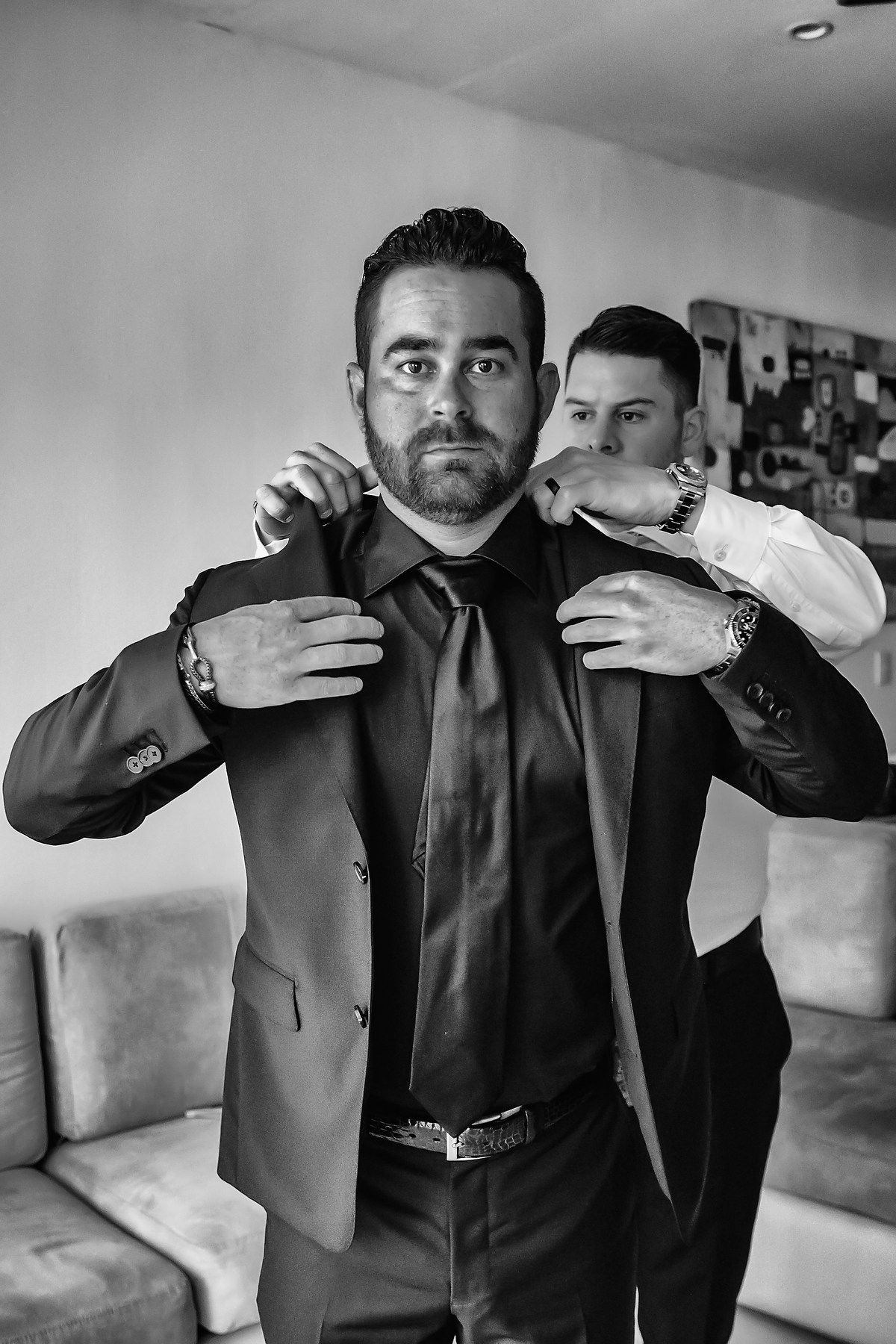 Black and white sequence showing someone adjusting the collar of a formal black suit jacket.