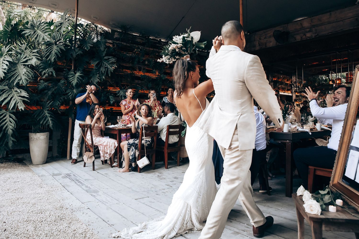 Wedding reception celebration with guests dancing and mingling under rustic covered outdoor venue.