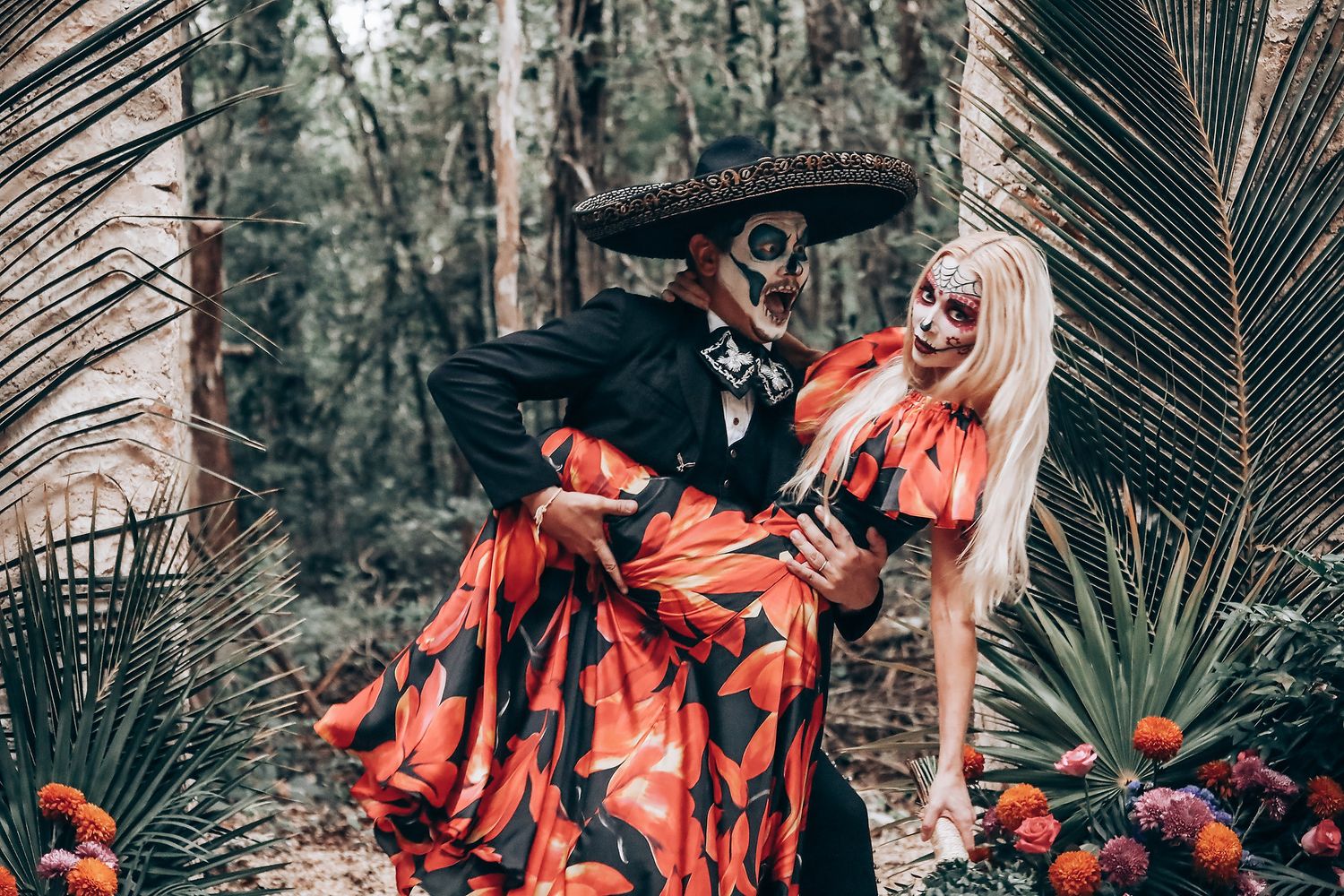 Gothic wedding photoshoot featuring dramatic red floral dresses in tropical garden setting.
