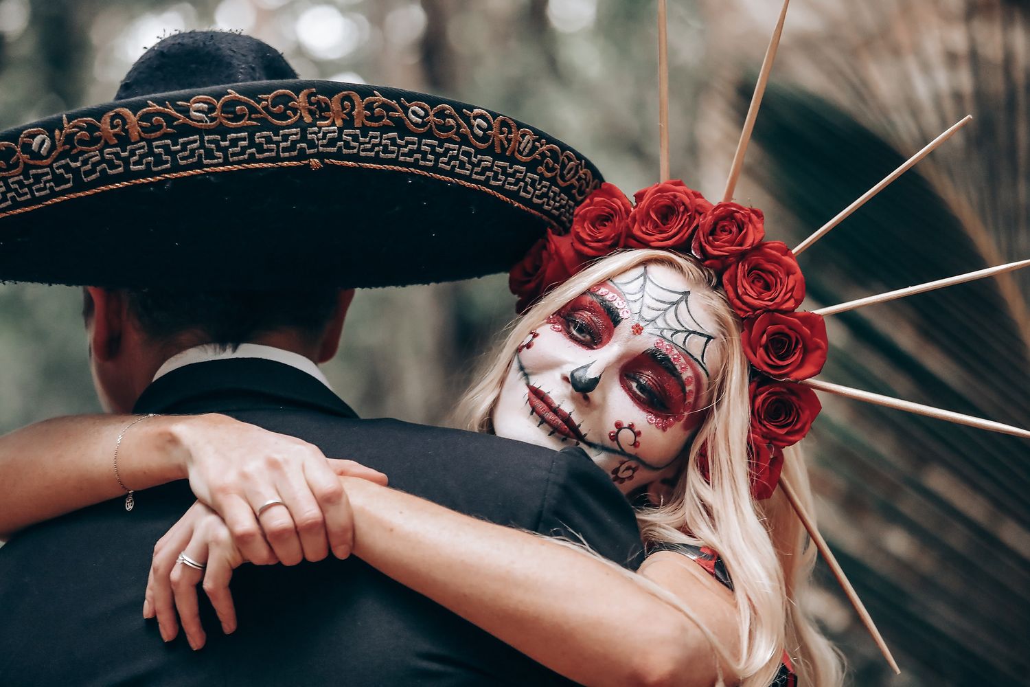 Artistic Halloween themed portrait with red roses and white face paint against moody forest backdrop.