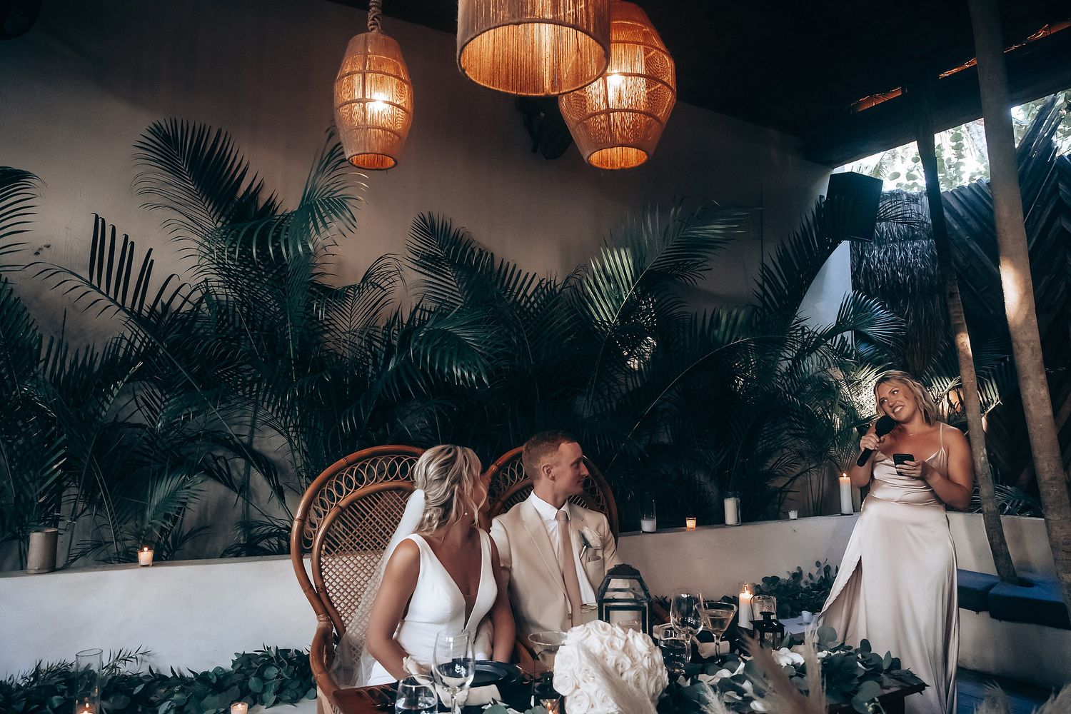 Reception setting with wicker peacock chair and hanging lanterns creating a tropical ambiance.
