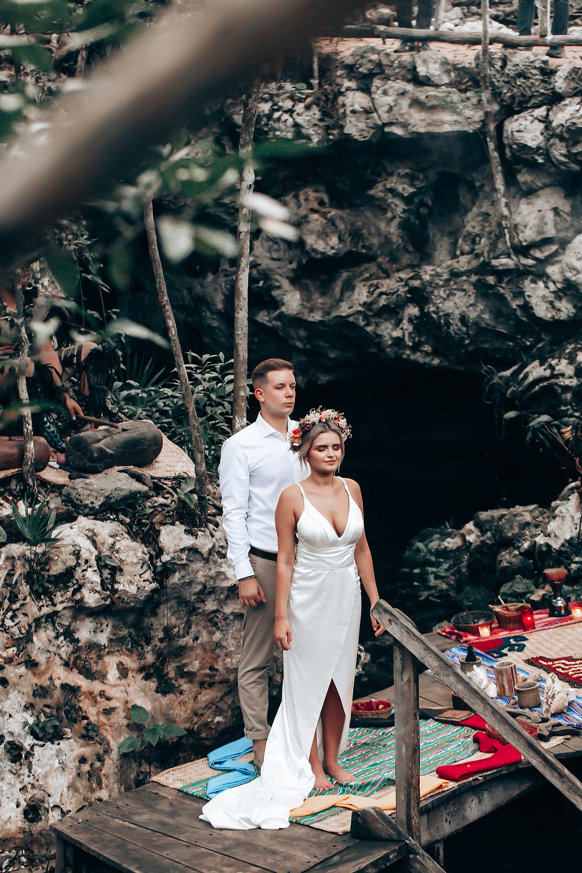 A couple posing on wooden platforms against a rocky backdrop during their wedding shoot.