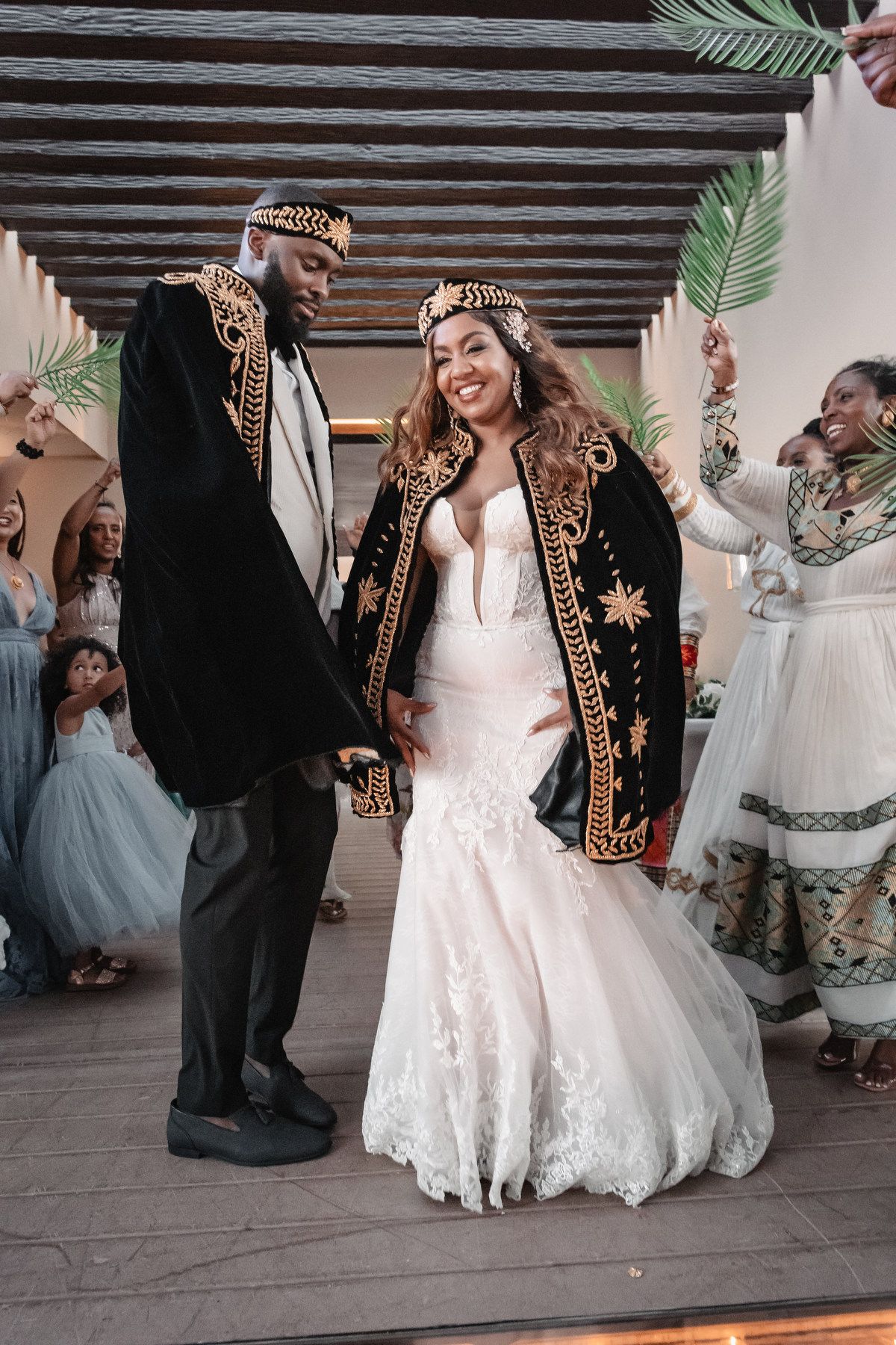 Bride and groom in ornate black and gold African ceremonial attire dancing at their wedding reception.