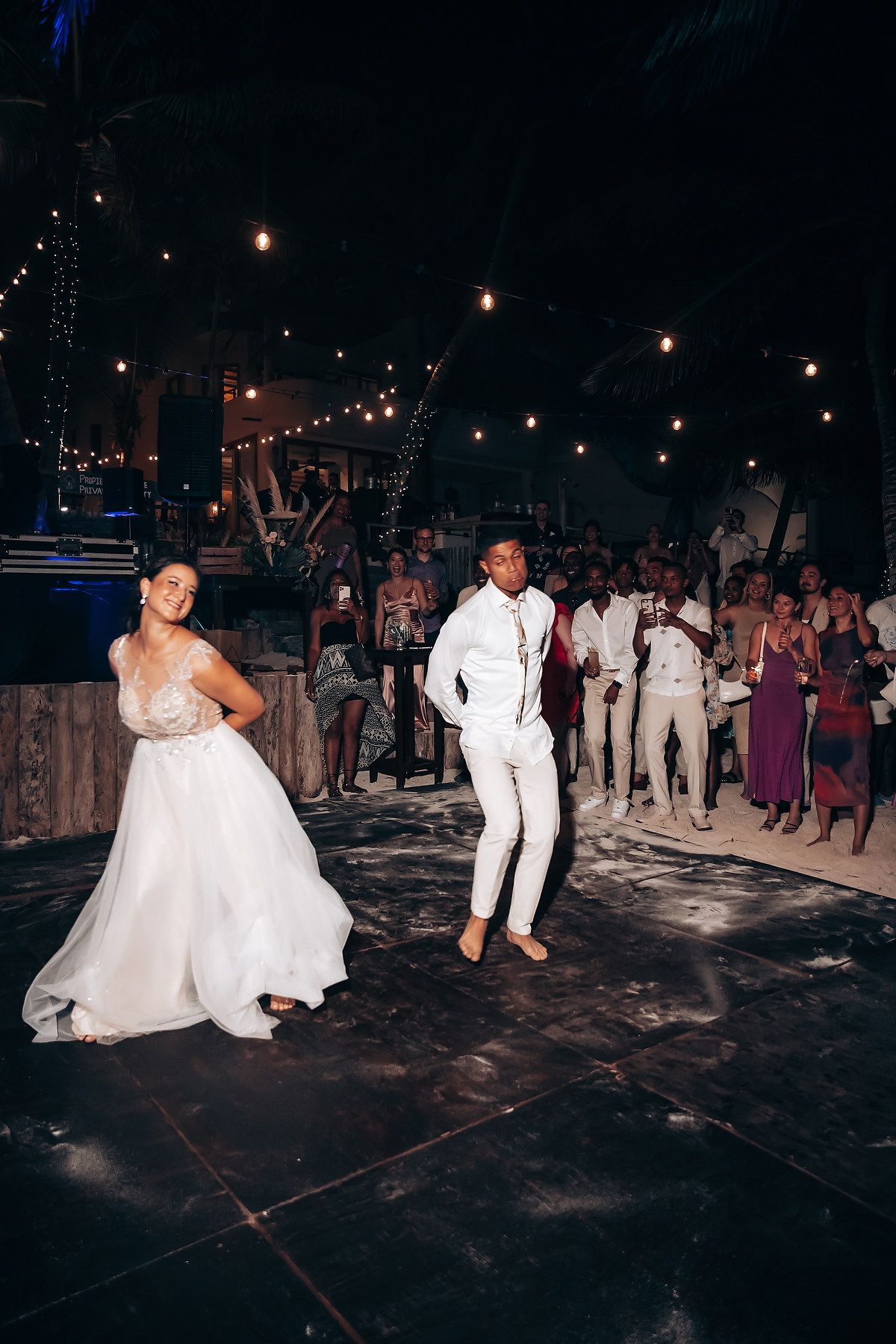 Wedding reception dance party at night with string lights overhead.