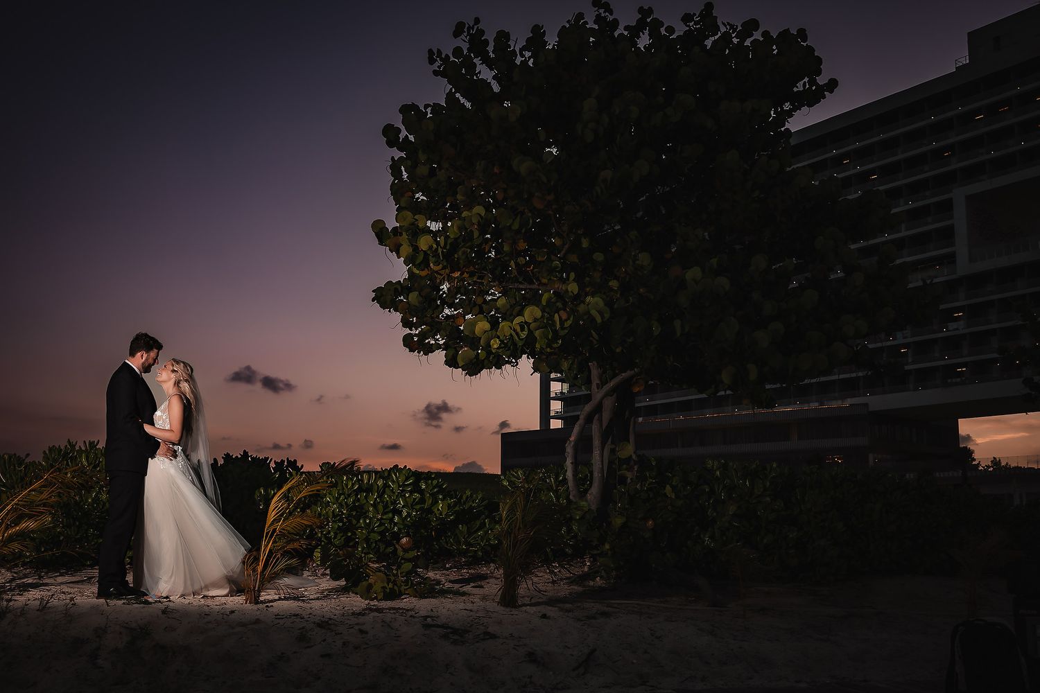 Silhouette of wedding couple against dramatic sunset sky.