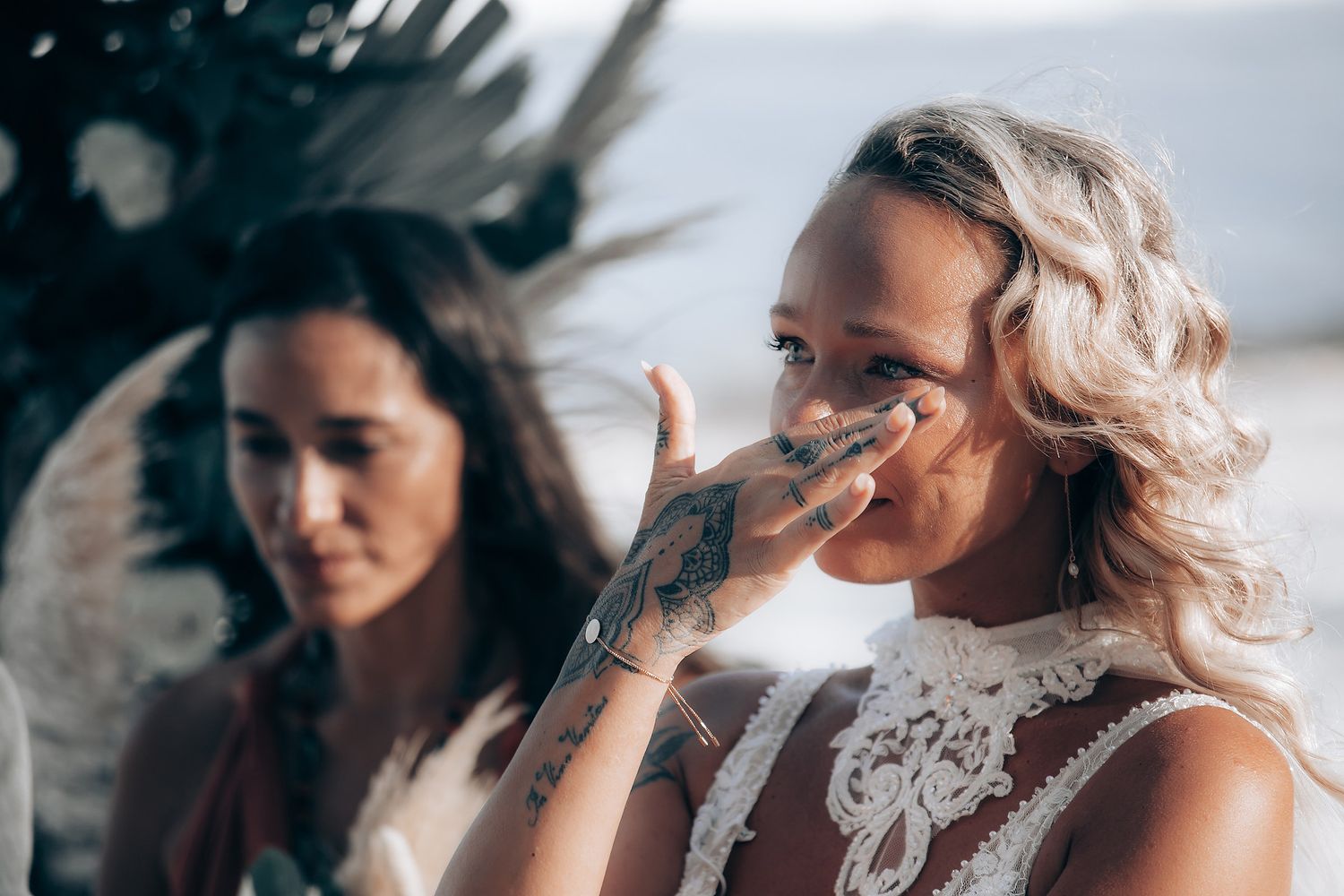 An emotional moment during a wedding ceremony with attendees in white lace.