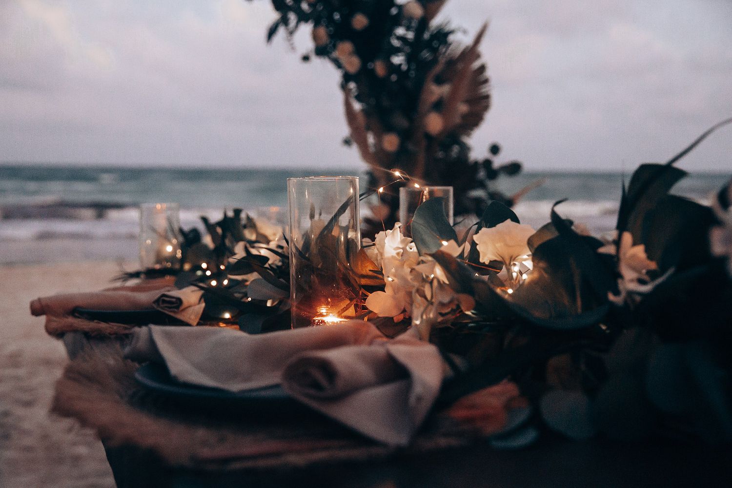 Beach wedding decor with moody lighting and floral arrangements.