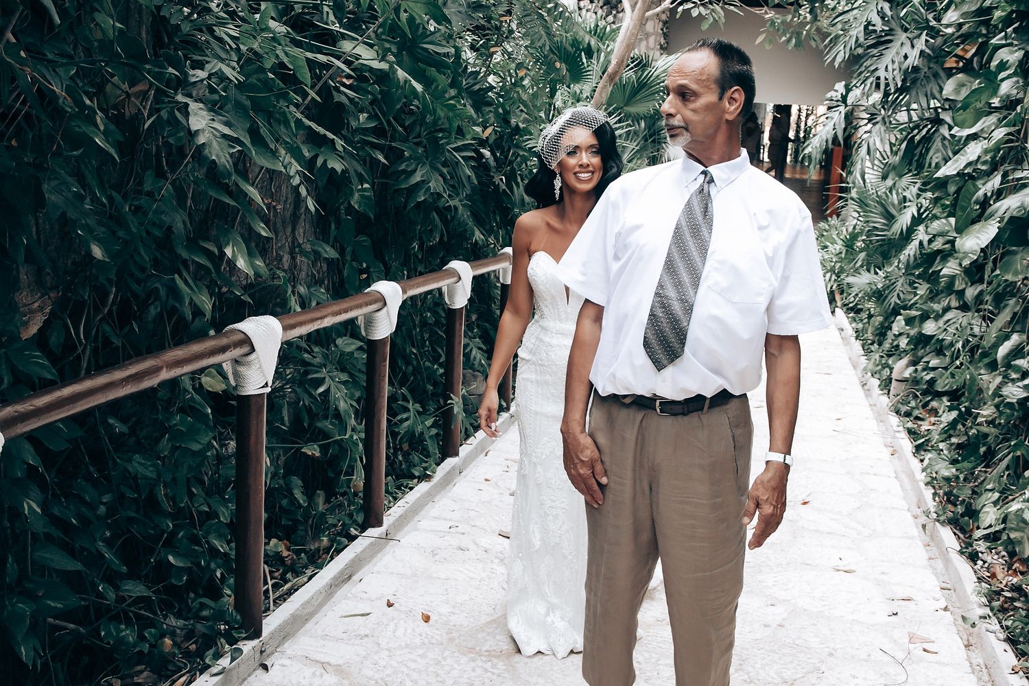 Wedding guests walking along a scenic outdoor path lined with lush greenery.