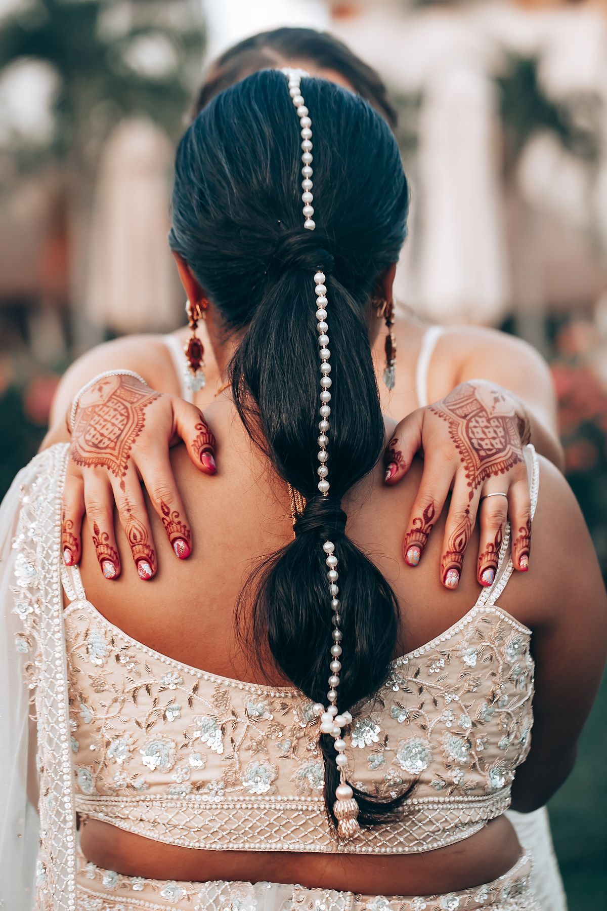 Intricate henna designs and pearl hair accessories on bride wearing traditional Indian wedding attire.