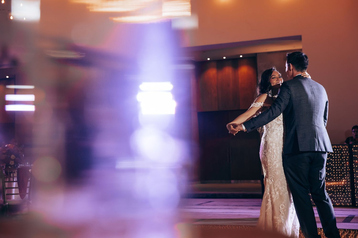 Couple dancing in elegant attire with motion blur effects and ambient lighting.