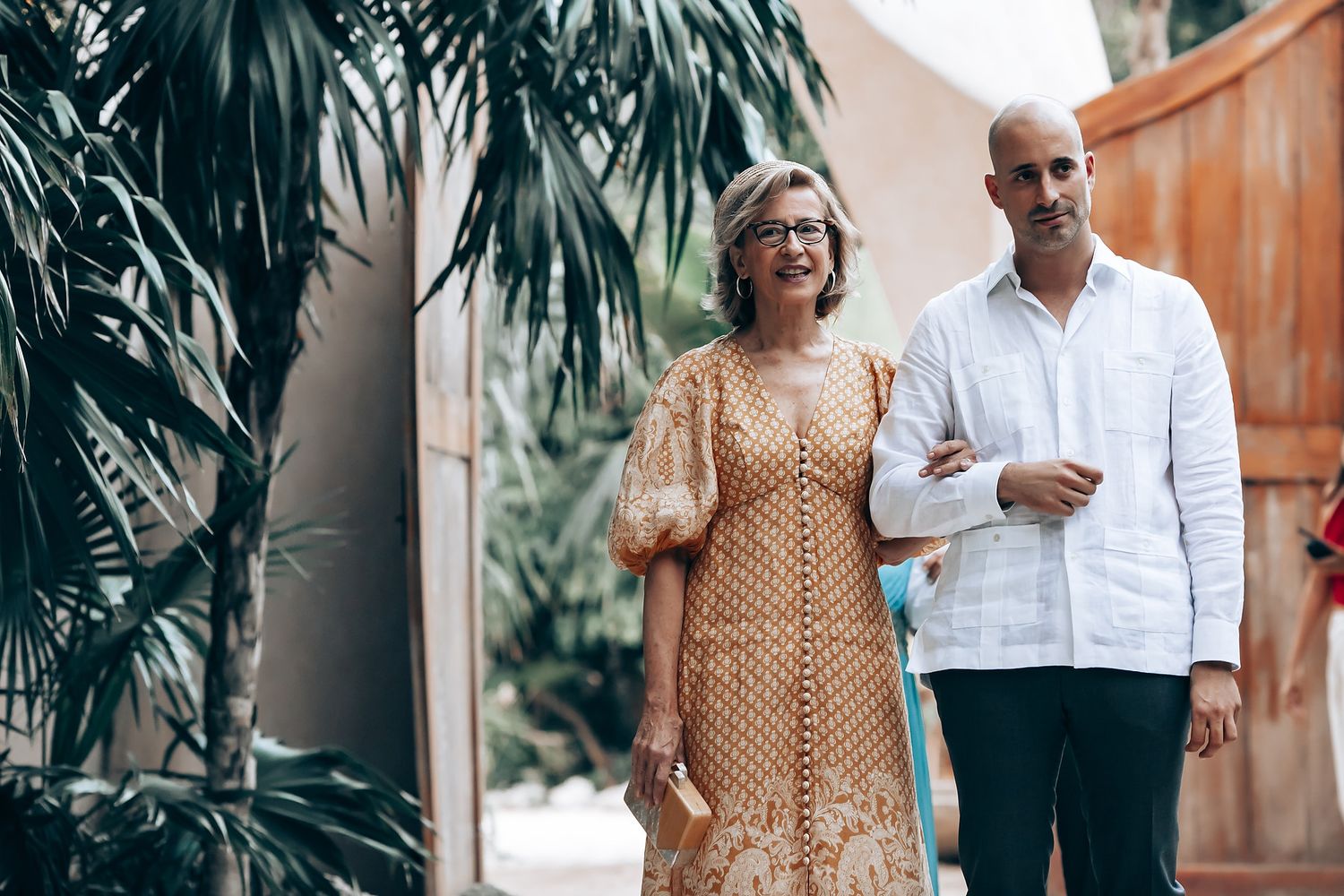 A romantic tropical wedding photoshoot with palm trees and natural lighting in an outdoor setting.