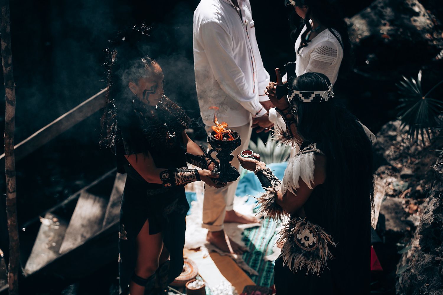 People gathered around a glowing blue and orange flame during an outdoor ceremony.