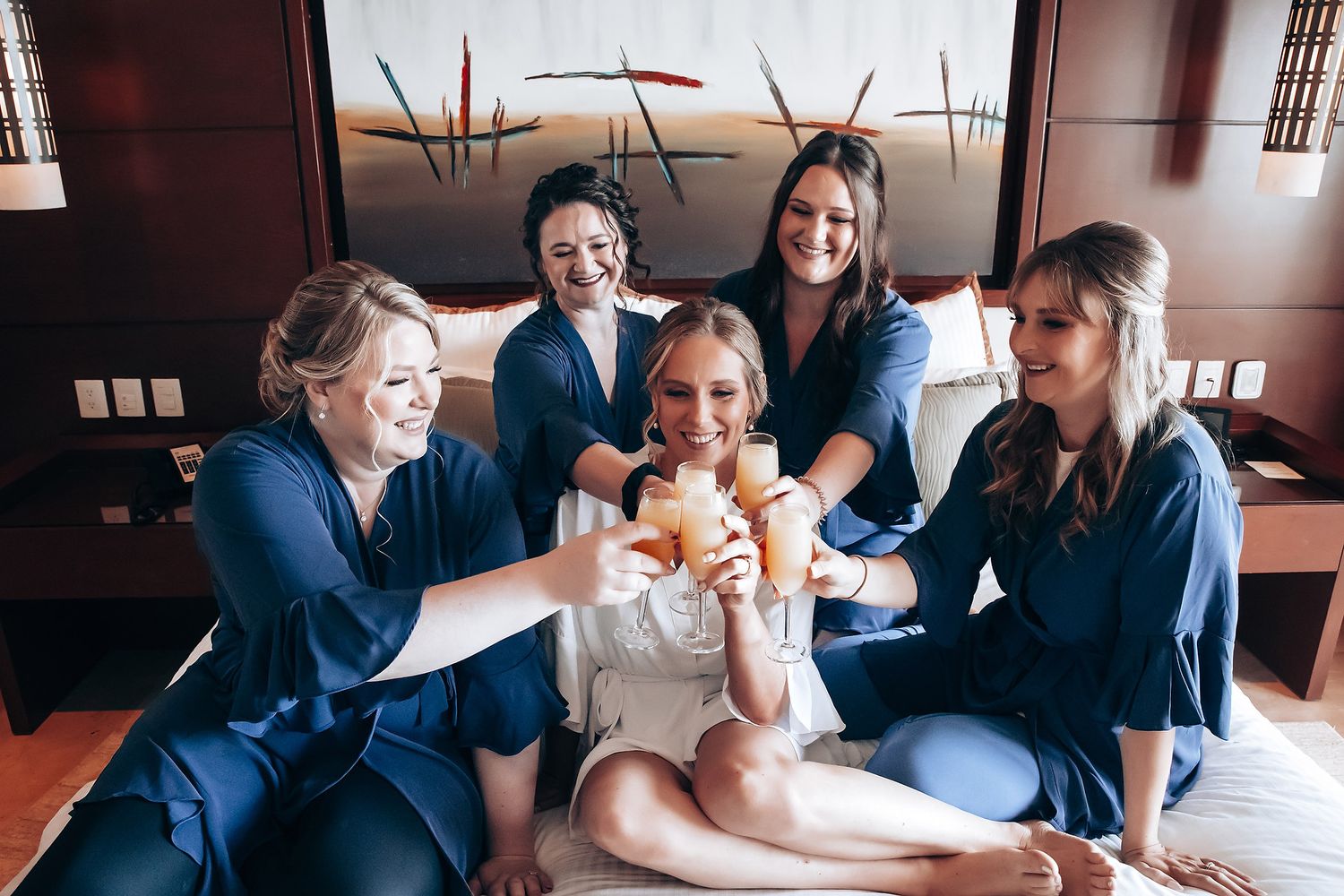 A group of five young women in casual clothing sitting together and smiling at the camera.