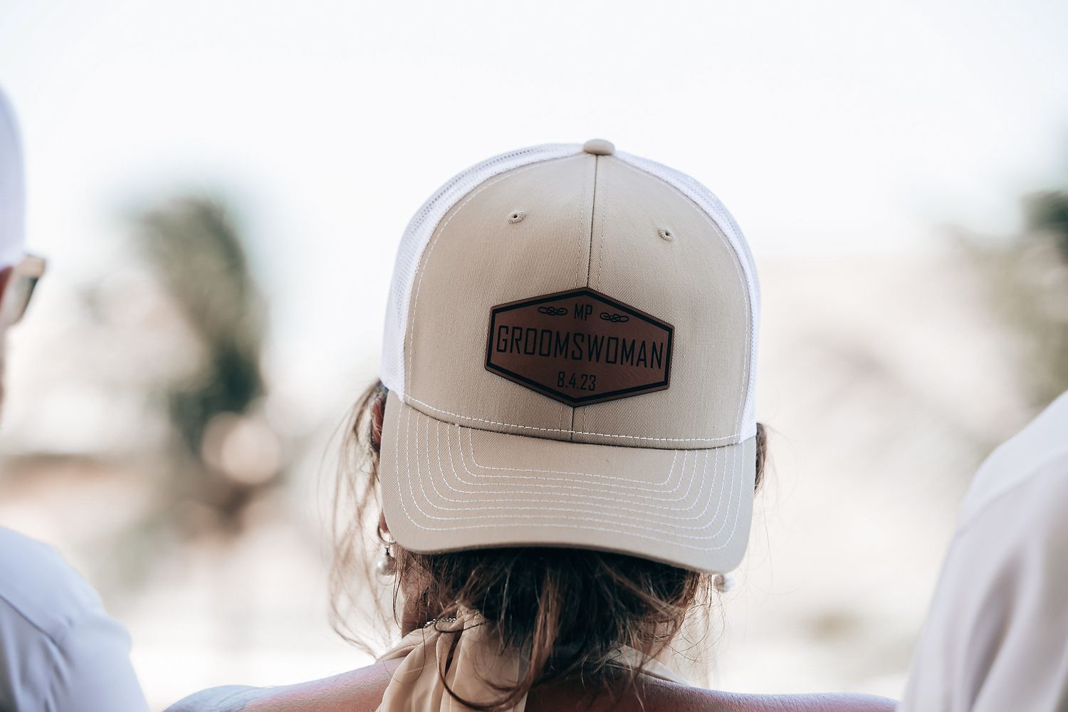 A person wearing a baseball cap with a logo is seen from behind.