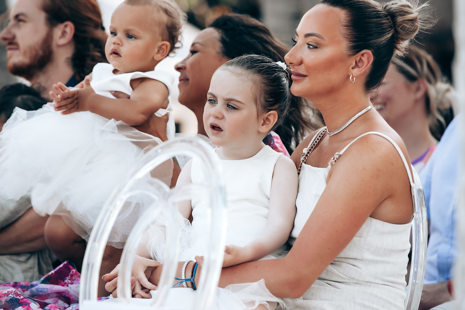A group of wedding guests in white attire dance together at an outdoor celebration party.