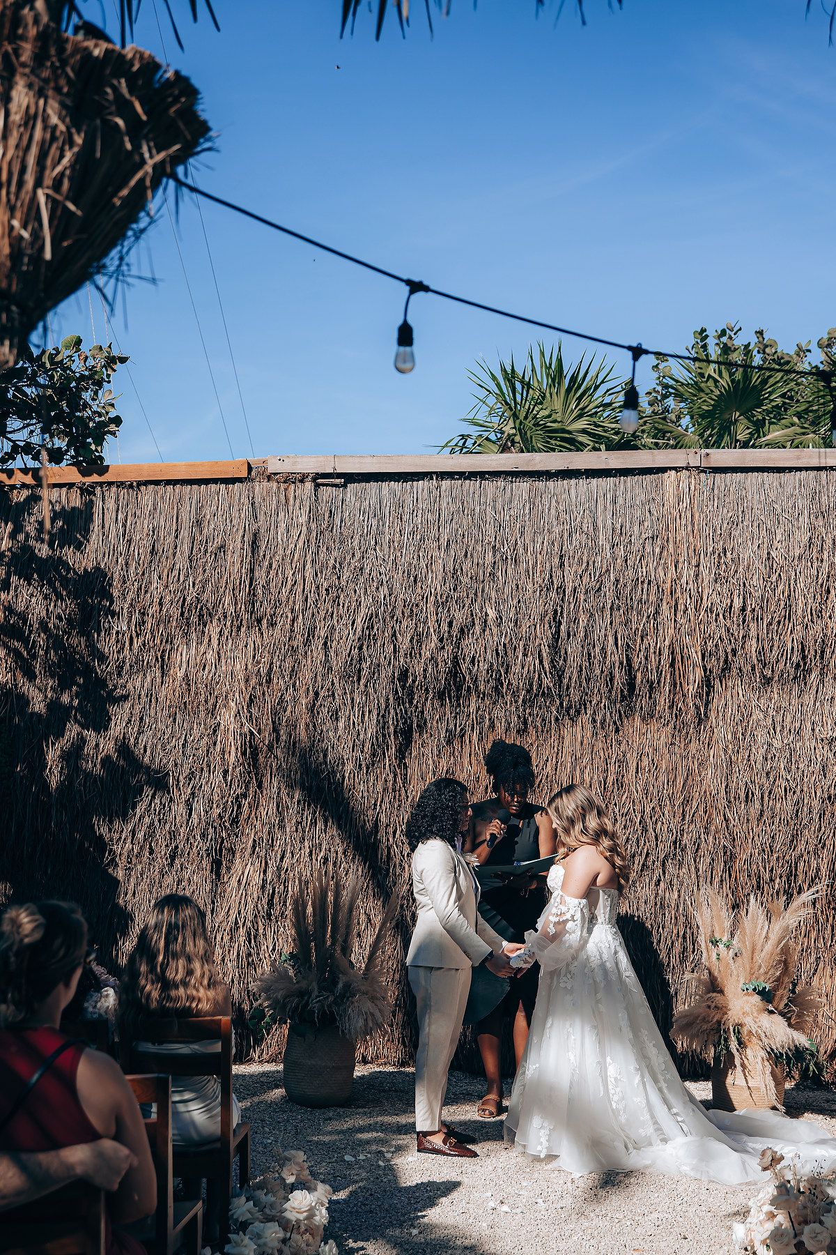 Wedding celebration under a thatched roof pavilion with string lights and tropical decor.