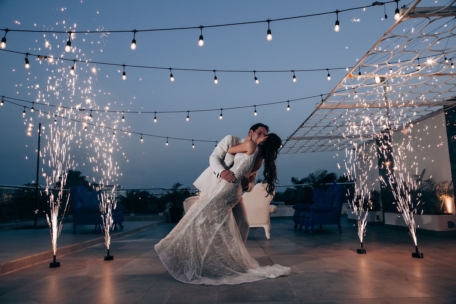 Dramatic wedding dance with sparkler fountains and string lights creating magical atmosphere.