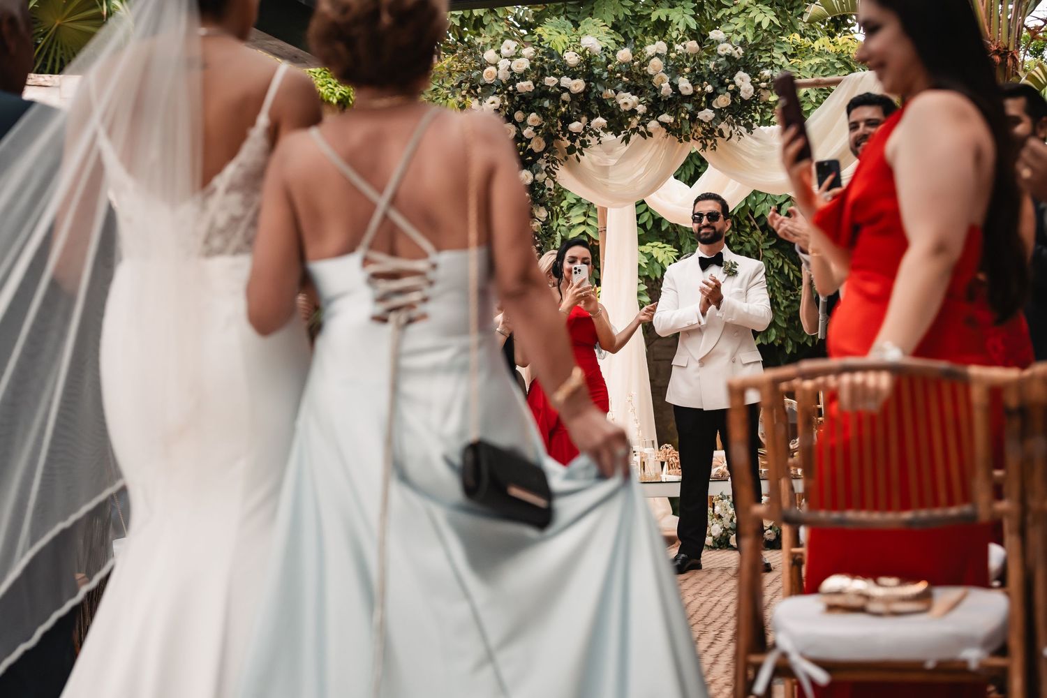 Wedding celebration on an elegant covered patio with white drapes and floral decorations.