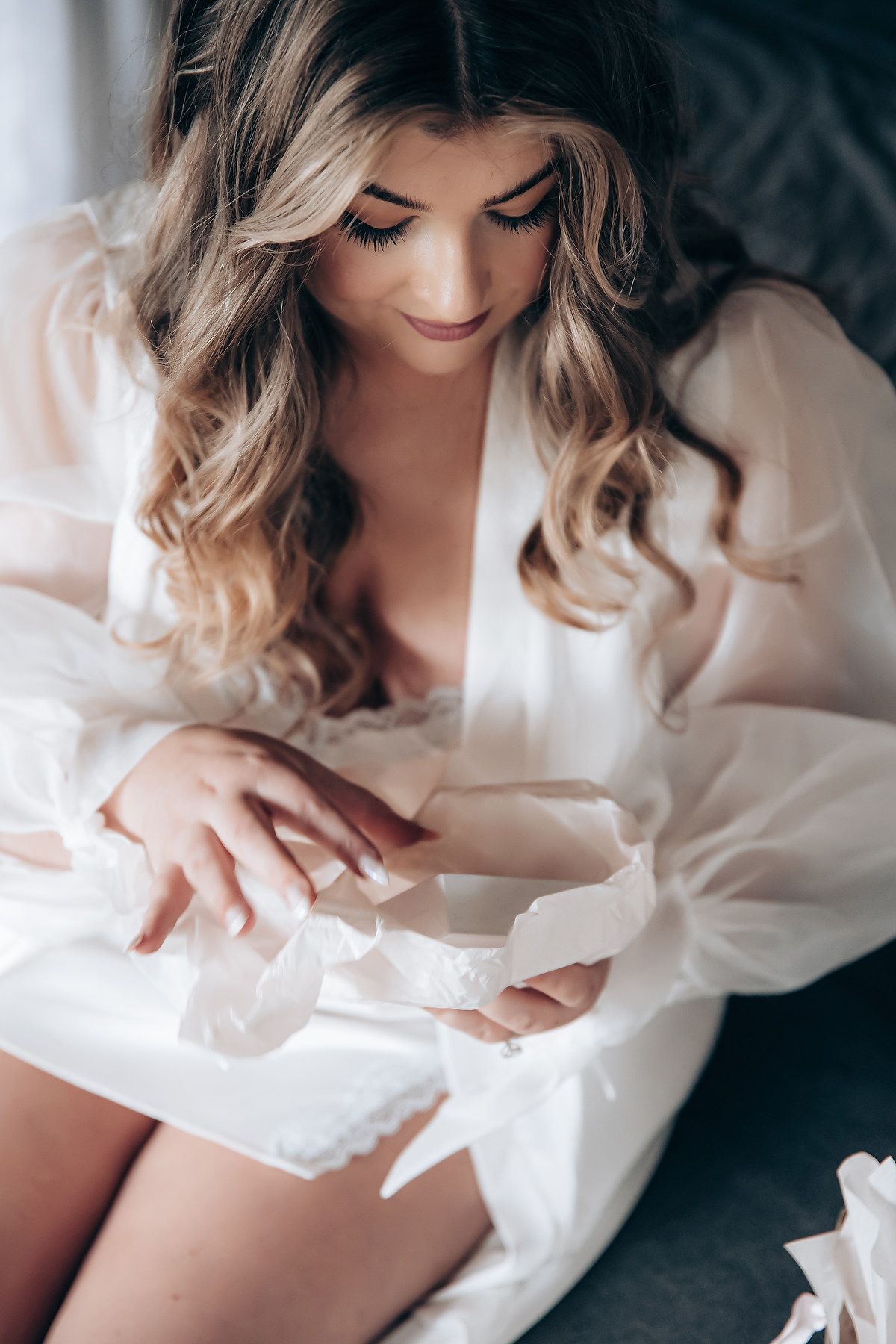 Intimate boudoir photography session featuring soft white fabric and romantic lighting.