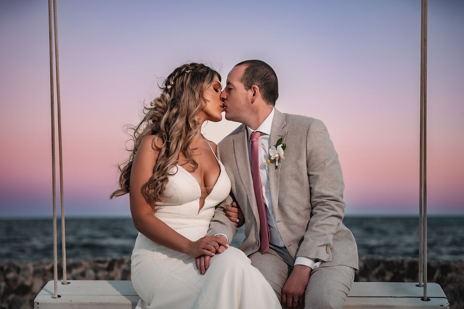 Romantic sunset wedding portraits captured against an ocean backdrop.