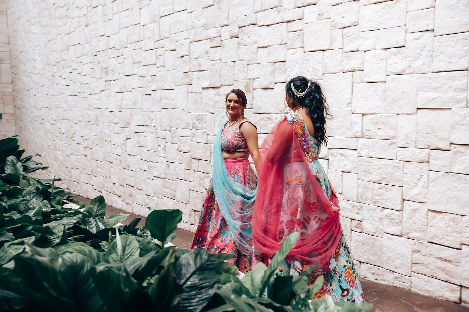 Outdoor photoshoot with pink outfits against white stone wall.