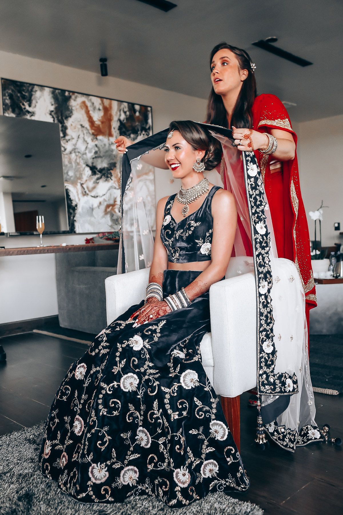 Traditional Indian bridal preparation scene with ornate black and silver lehenga.
